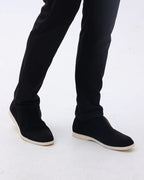 Person wearing black slip-on shoes with a white background
