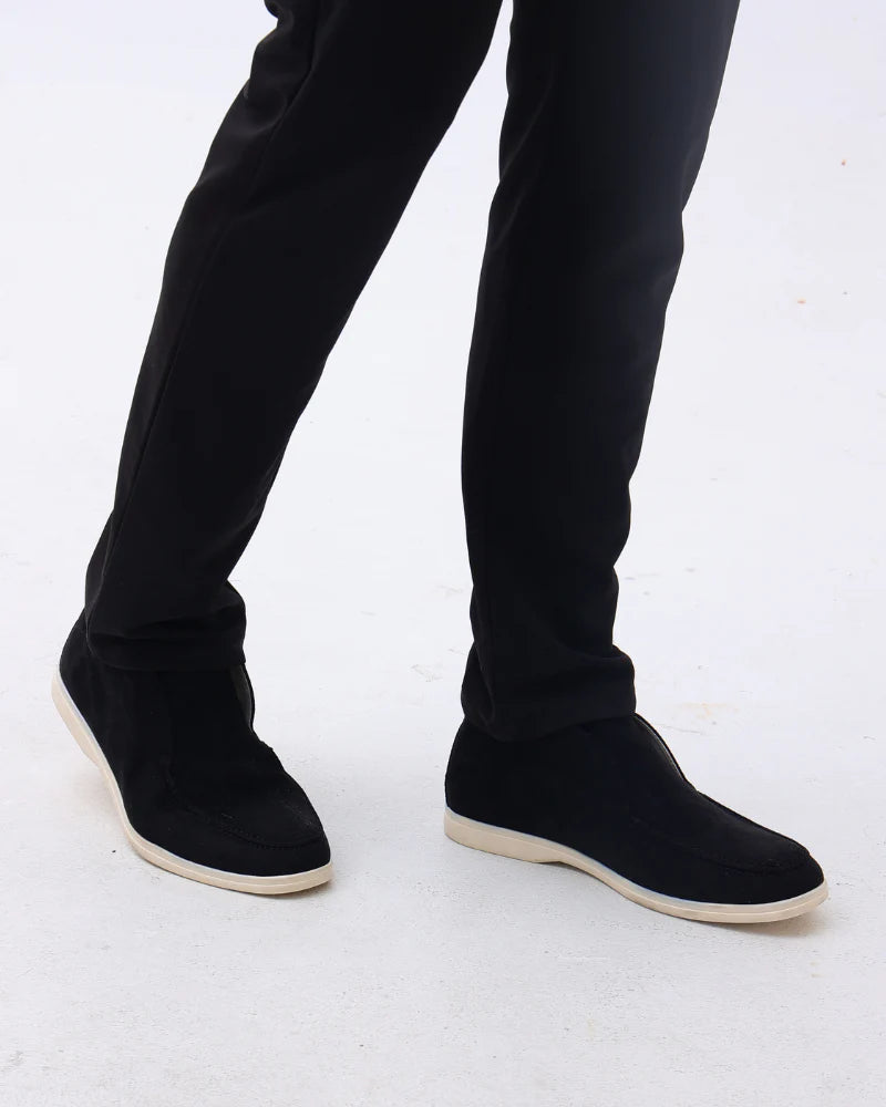 Person wearing black slip-on shoes with a white background