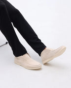 Person wearing beige slip-on shoes and black pants on a white background