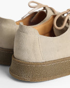 Close-up of a pair of beige and brown shoes with suede texture.