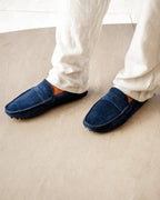 Blue slippers worn with white pants on a beige carpet