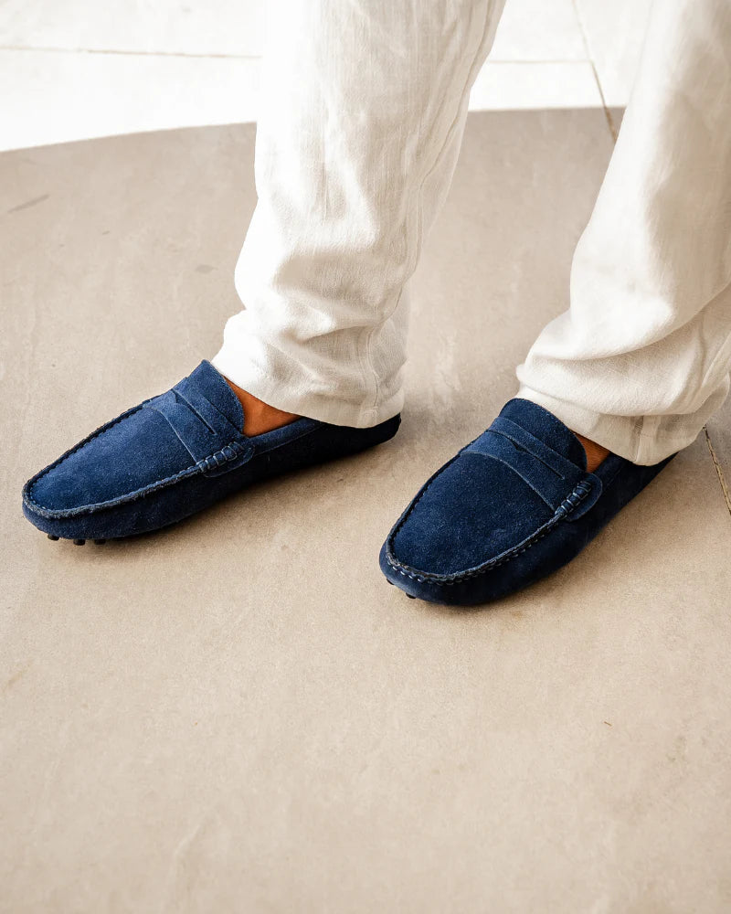 Blue slippers worn with white pants on a beige carpet