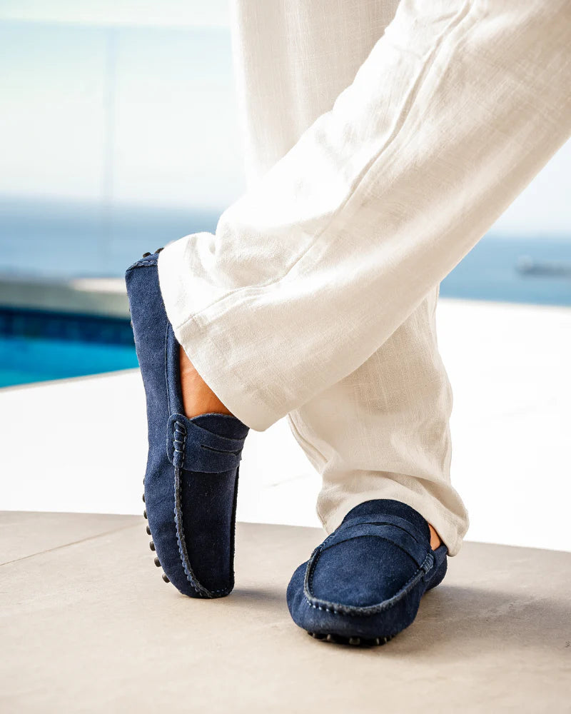 Navy loafers worn with white pants by a poolside.