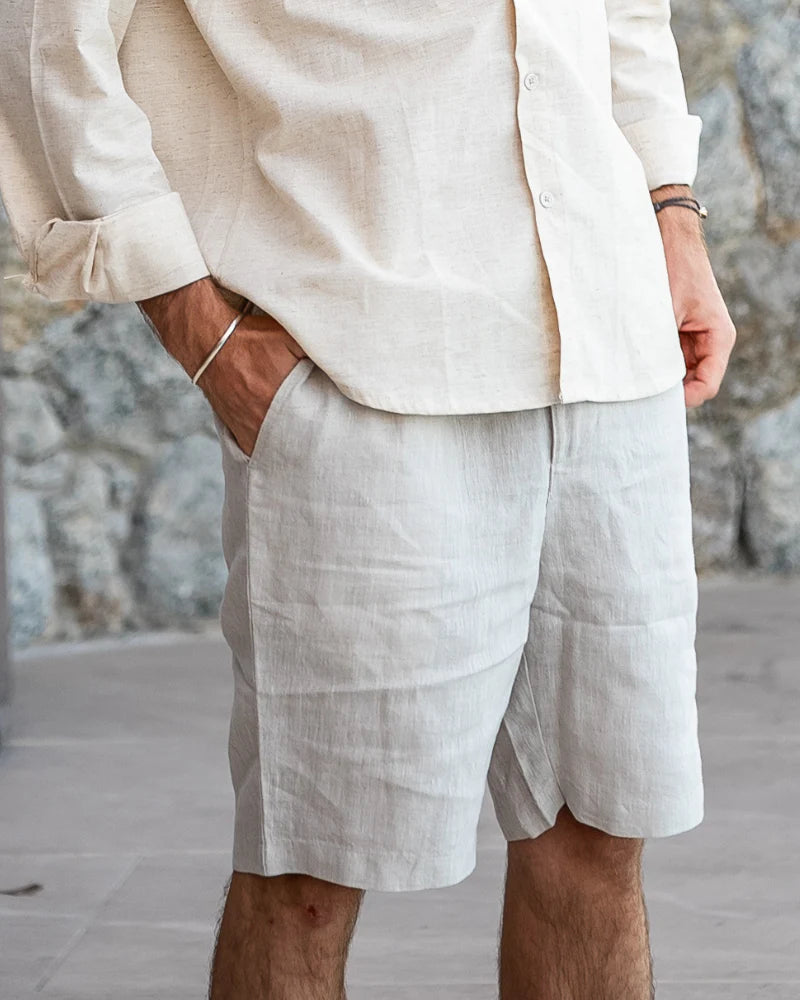 Man wearing the Casablanca linen shorts with a navy blue polo shirt at a seaside cafe.
