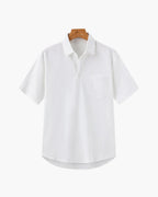 White shirt on a wooden hanger against a white background