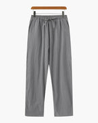 Gray pants on a wooden hanger against a white background