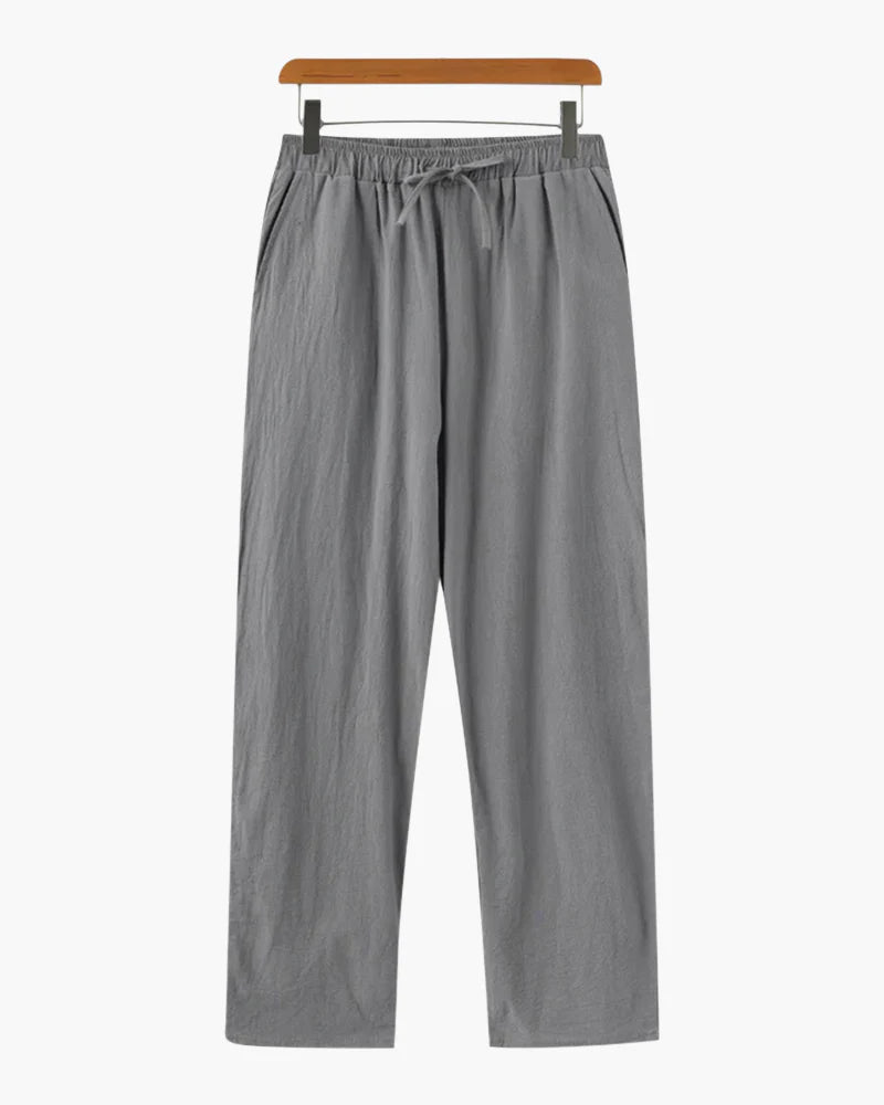 Gray pants on a wooden hanger against a white background