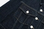 Close-up of a dark blue denim jacket with button details on a white background