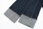 Close-up of dark blue jeans with gray cuffs on a white background