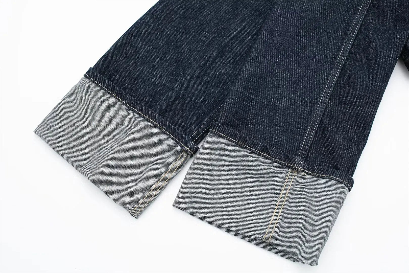 Close-up of dark blue jeans with gray cuffs on a white background