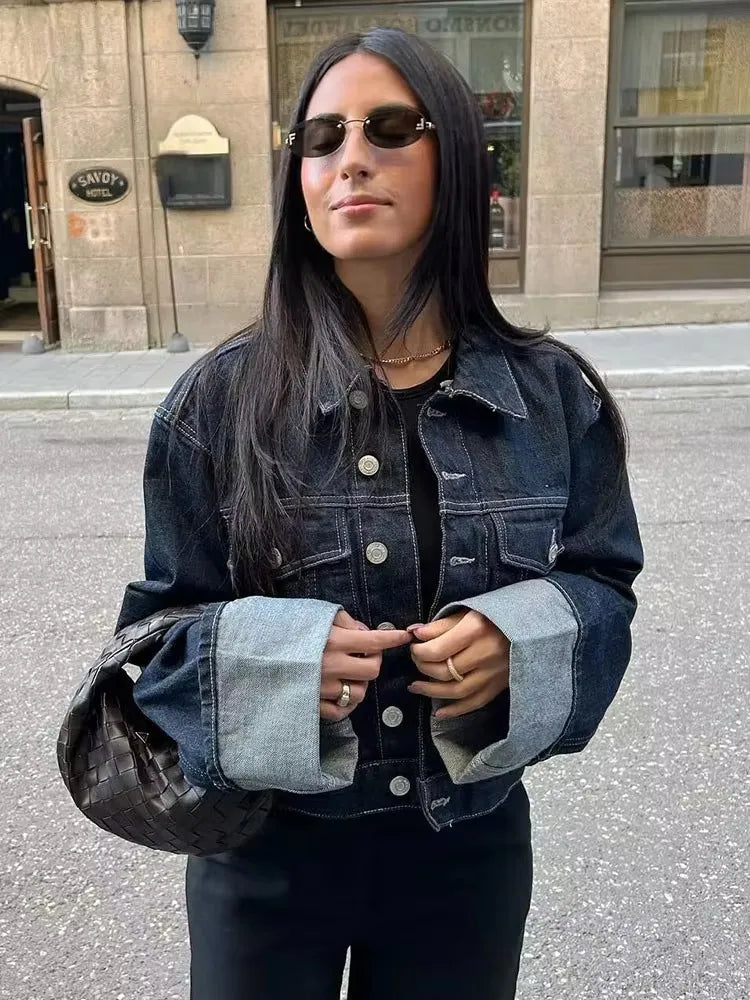 Person wearing a denim jacket and sunglasses on a street.