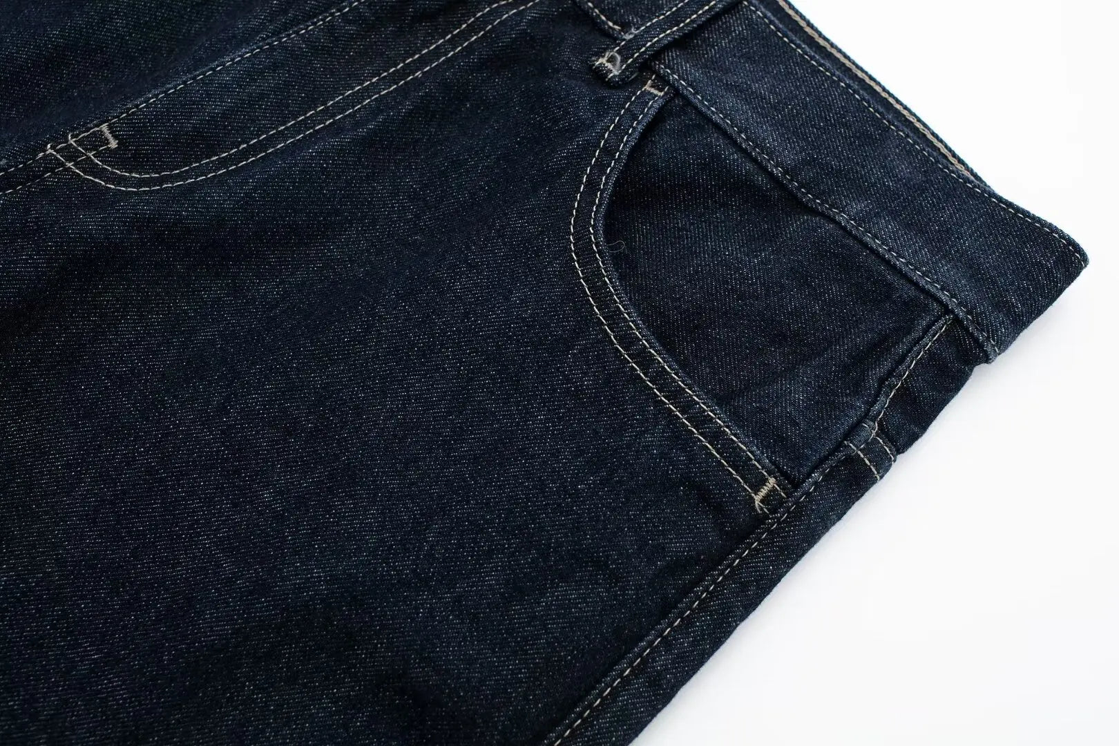 Close-up of dark blue jeans on a white background