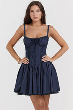 Woman wearing a navy blue dress with lace details on a white background