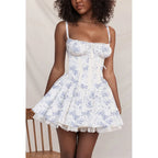 Woman wearing a white floral dress with lace trim against a neutral background