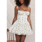 Woman wearing a white floral dress with thin straps against a neutral background