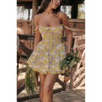 Woman in a yellow floral dress standing in a rustic outdoor setting