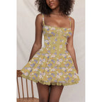 Woman wearing a yellow floral dress against a plain background