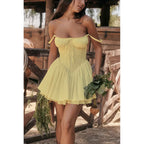 Woman in a yellow dress holding vegetables in a rustic setting
