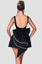 Black dress with a large bow detail on the back, worn by a person against a plain background.