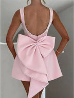 Pink dress with a large bow detail on a plain background