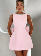 Woman wearing a pink dress with pearl details against a neutral background