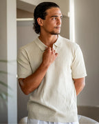 Man wearing a light-colored ribbed polo shirt indoors