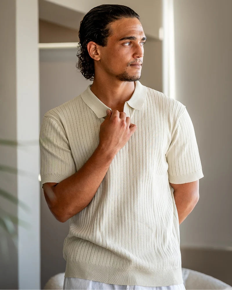 Man wearing a light-colored ribbed polo shirt indoors