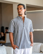 Man wearing a gray and white striped shirt in a living room setting
