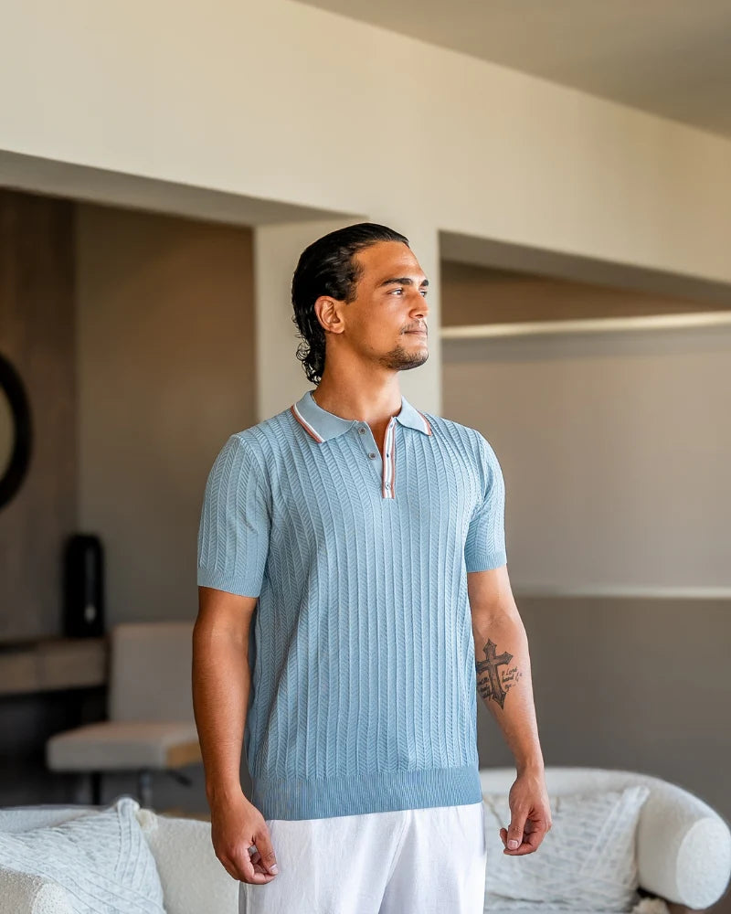 Man wearing a light blue ribbed polo shirt in a modern indoor setting