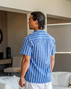 Man wearing a blue striped shirt in a living room setting
