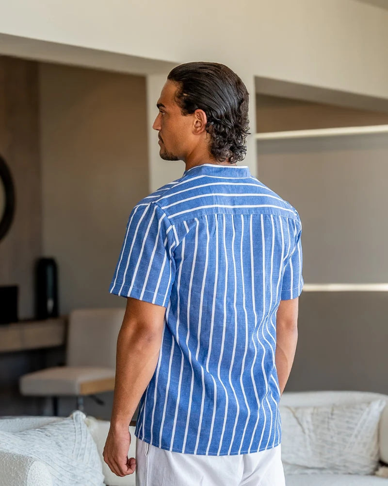 Man wearing a blue striped shirt in a living room setting