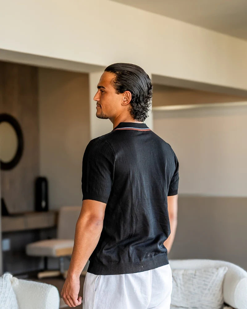 Man wearing a black polo shirt in a room with neutral decor