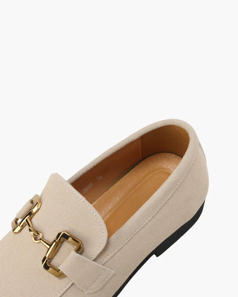 Beige loafer with gold buckle on a white background