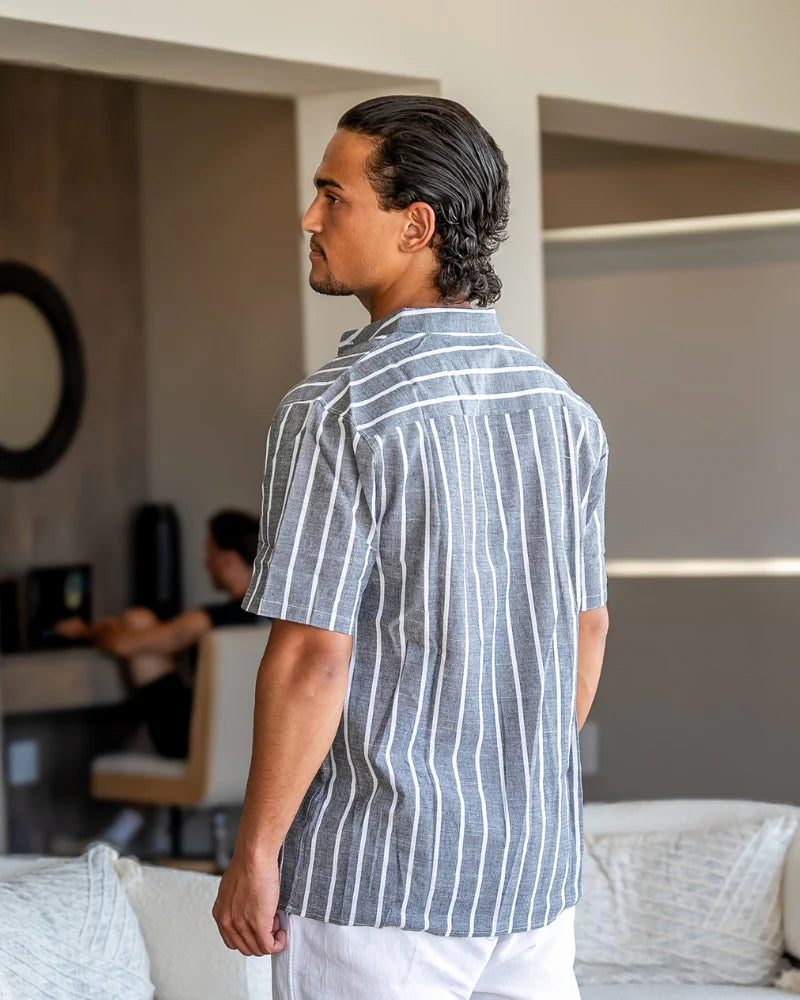 Man wearing a blue striped shirt in a modern living room.