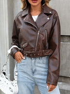 Person wearing a brown leather jacket and light blue jeans, holding a white handbag.