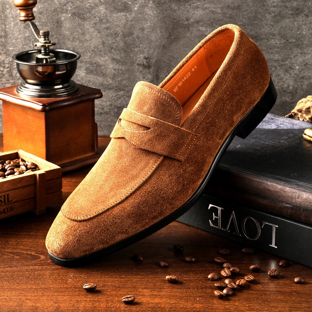 Brown suede loafer shoe on a wooden surface with coffee beans and a grinder.