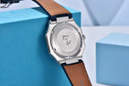 Silver watch with brown leather strap on a blue geometric background