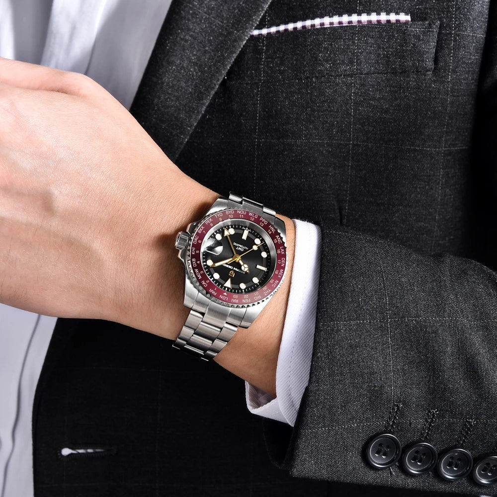 Person wearing a silver watch with a black and red face on a suit sleeve.