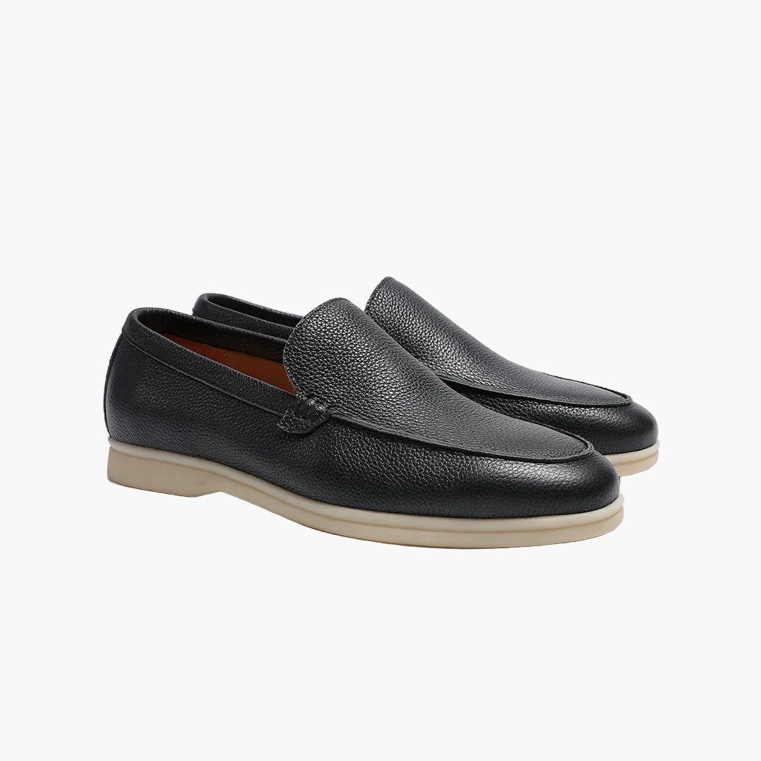 Pair of black leather loafers on a light gray background