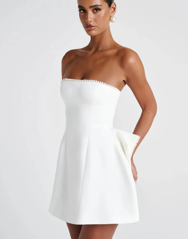 Woman wearing a strapless white dress on a plain background