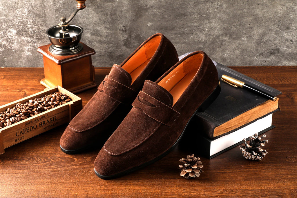 Brown loafers on a wooden surface with coffee beans and a grinder.