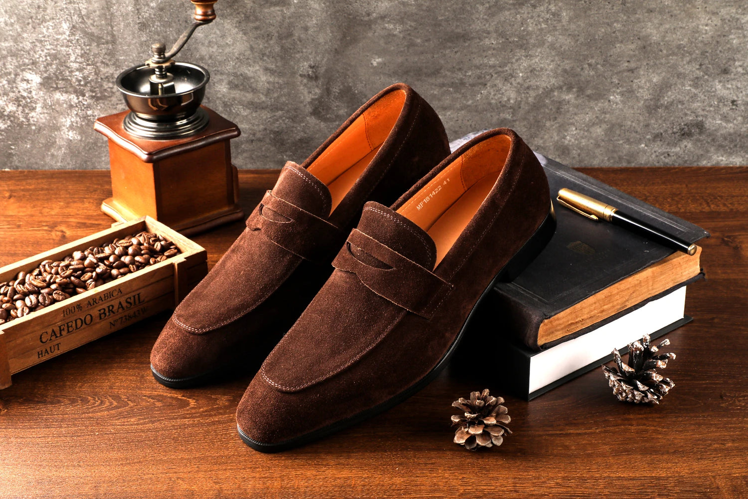 Brown loafers on a wooden surface with coffee beans and a grinder.