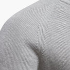 Close-up of a gray sweater sleeve with ribbed texture on a white background