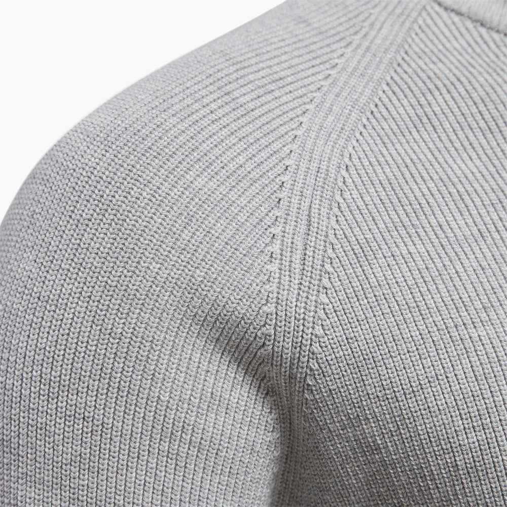 Close-up of a gray sweater sleeve with ribbed texture on a white background
