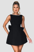 Woman wearing a black dress with pearl details against a neutral background