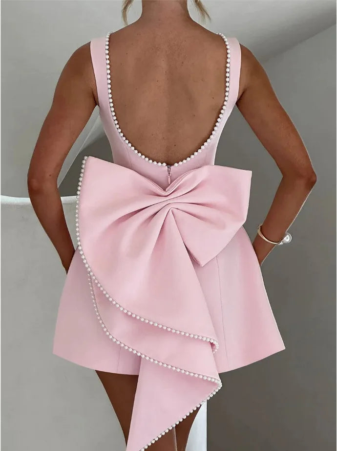 Pink dress with a large bow detail on a plain background