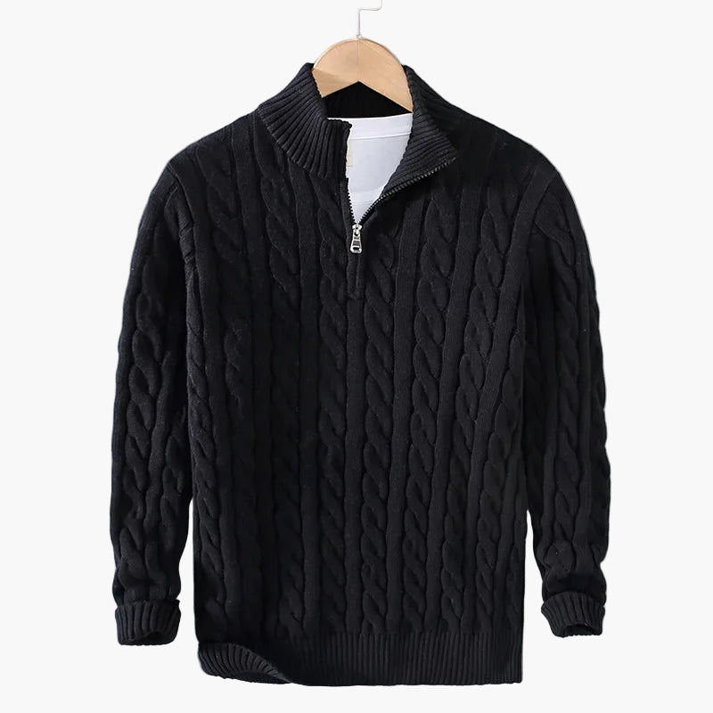 Black cable knit sweater with a zipper on a hanger against a gray background