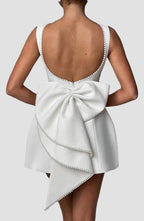 White dress with a large bow detail on the back against a gray background