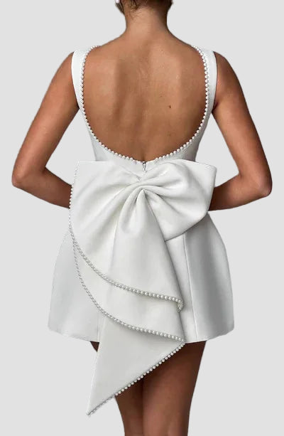 White dress with a large bow detail on the back against a gray background