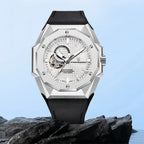 Luxury watch with a black strap on a rocky surface with a light blue background